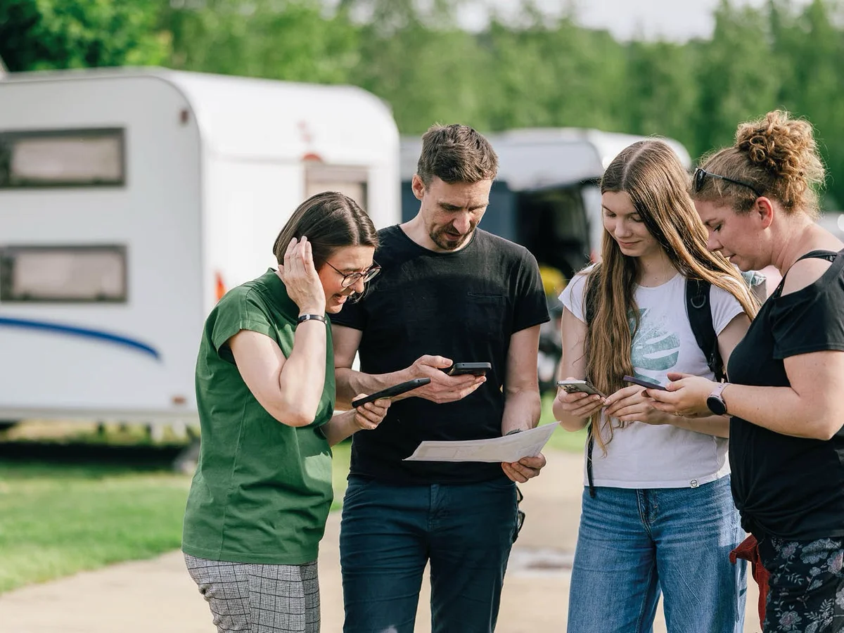 Gruppe spielt eine Handy-Schnitzeljagd mit Smartphone und Schatzkarte.